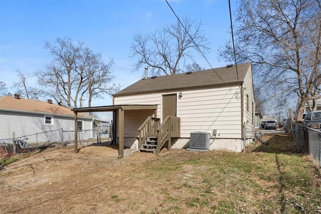 rear view of house with cooling unit, a carport, and fence