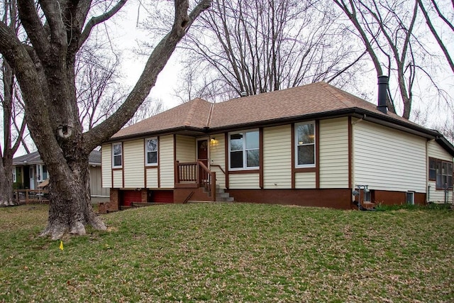 ranch-style home with a shingled roof and a front yard