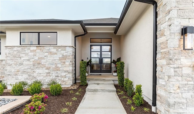 entrance to property featuring french doors, stone siding, and stucco siding