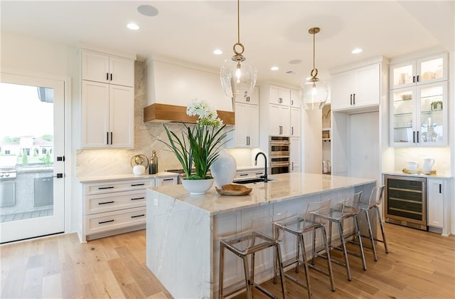 kitchen featuring white cabinetry, double oven, beverage cooler, and a sink