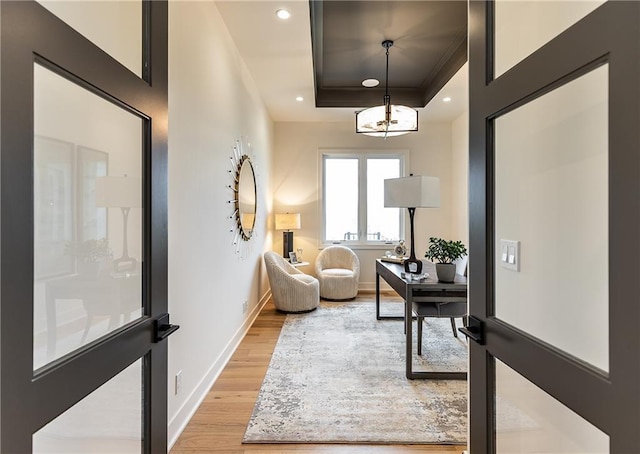 foyer entrance with a tray ceiling, light wood-type flooring, baseboards, and recessed lighting