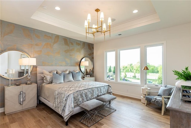 bedroom with light wood-type flooring, a tray ceiling, and wallpapered walls