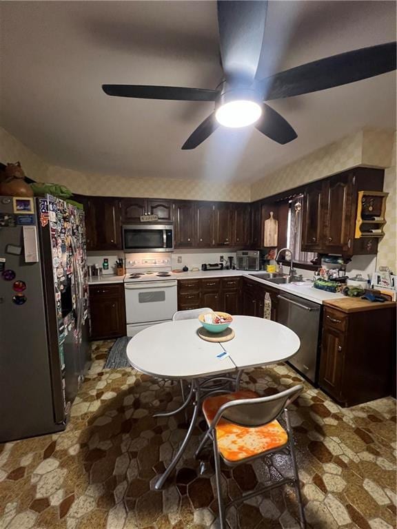 kitchen with dark brown cabinetry, stone finish floor, stainless steel appliances, and a sink