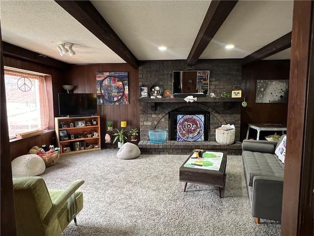 living room with beam ceiling, carpet flooring, wood walls, and a textured ceiling