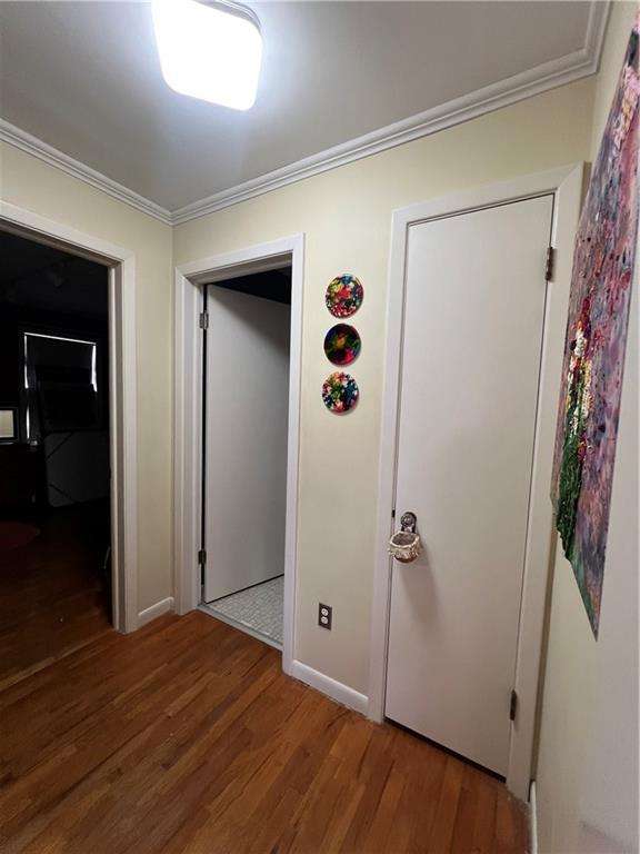 hallway featuring crown molding, baseboards, and wood finished floors