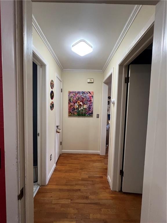 hallway featuring crown molding, wood finished floors, and baseboards