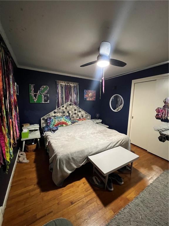 bedroom with ornamental molding and wood finished floors