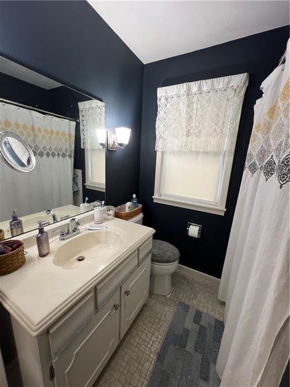 full bathroom with baseboards, toilet, and vanity