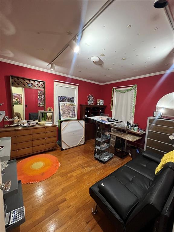 interior space featuring rail lighting, crown molding, and wood finished floors