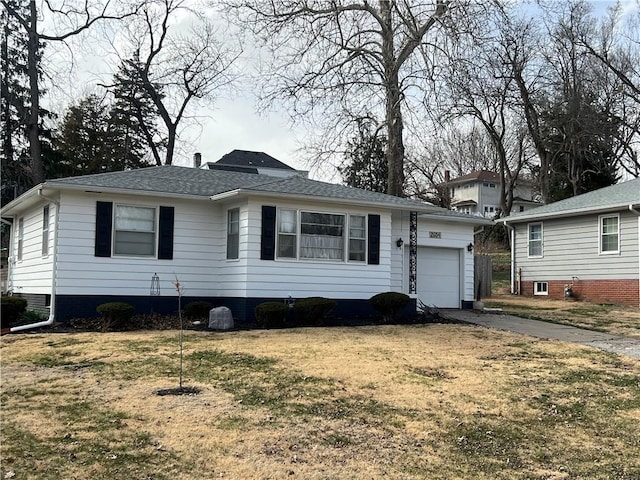 view of front facade featuring a front yard, an attached garage, driveway, and roof with shingles