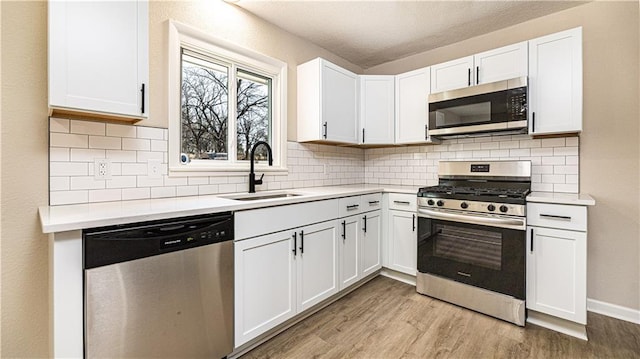 kitchen with a sink, light wood-type flooring, appliances with stainless steel finishes, and light countertops