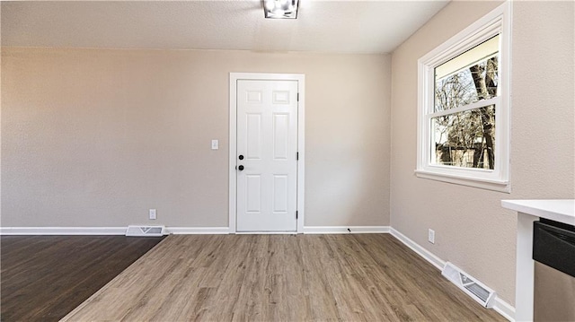 interior space with visible vents, baseboards, and wood finished floors