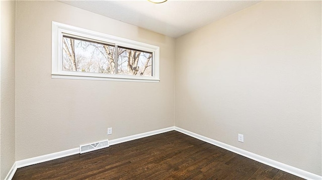 unfurnished room featuring dark wood finished floors, baseboards, and visible vents