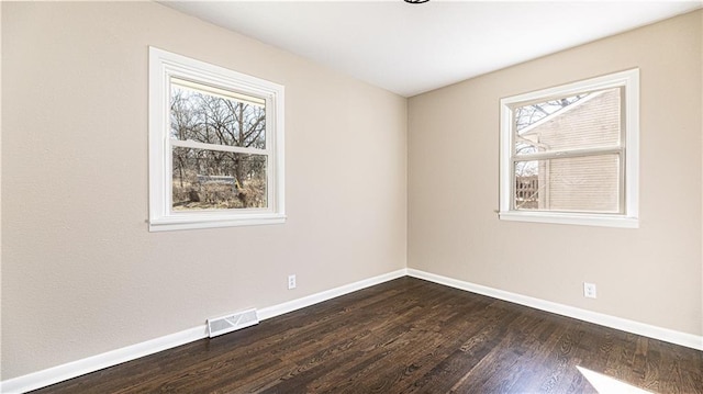 spare room with visible vents, baseboards, and dark wood-style flooring