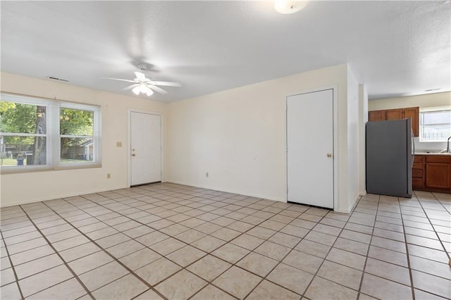 spare room featuring light tile patterned floors, a textured ceiling, baseboards, and ceiling fan