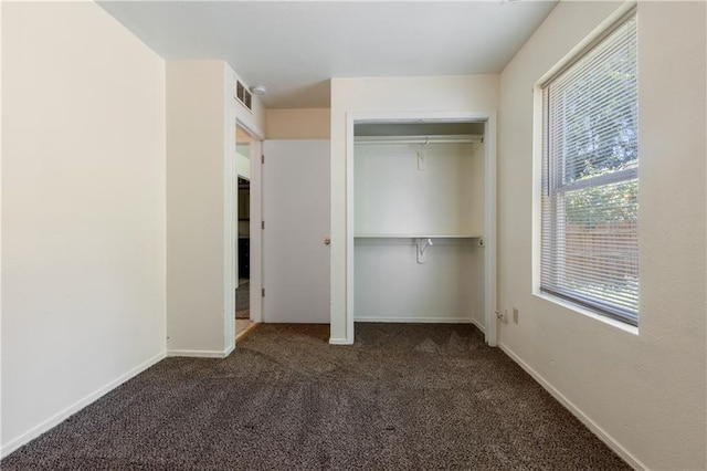 unfurnished bedroom with visible vents, baseboards, a closet, and dark carpet