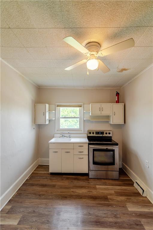 713 N 13th St, Atchison, KS 66002 - kitchen featuring stainless steel electric range oven, crown molding, white cabinetry, dark wood-type flooring, and ceiling fan