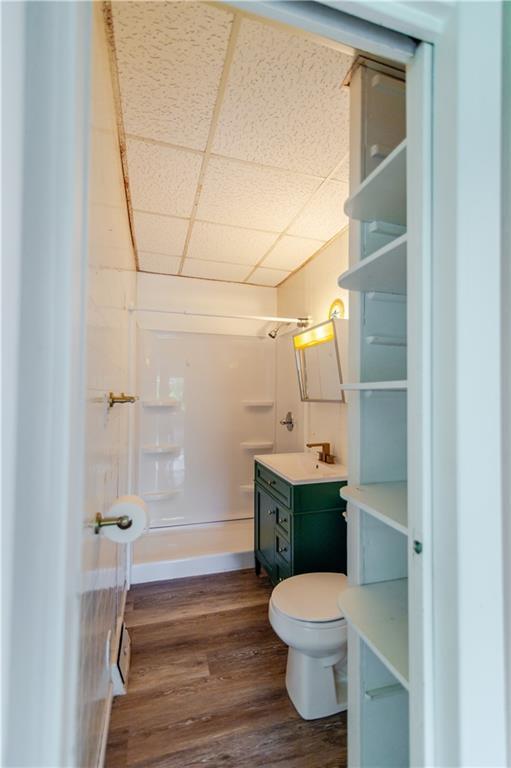 713 N 13th St, Atchison, KS 66002 - bathroom featuring vanity, a shower, a drop ceiling, and wood finished floors