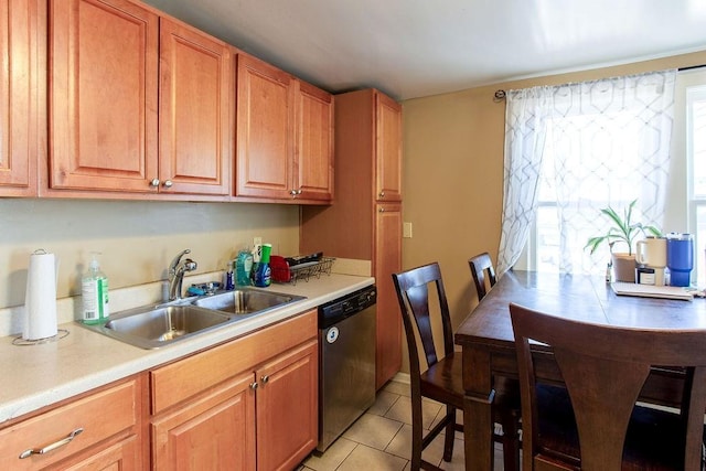 kitchen with brown cabinets, a sink, stainless steel dishwasher, light countertops, and light tile patterned floors