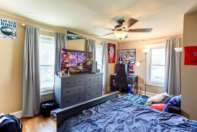 bedroom with ceiling fan, baseboards, multiple windows, and wood finished floors