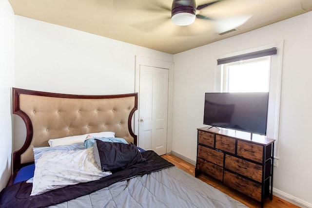 bedroom with ceiling fan, wood finished floors, visible vents, and baseboards