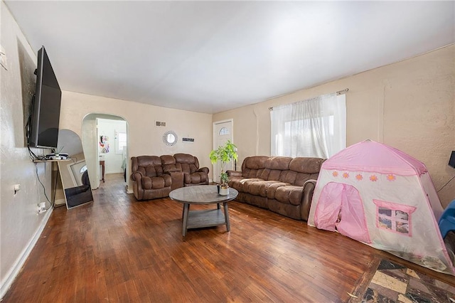 living room with baseboards, arched walkways, visible vents, and wood-type flooring