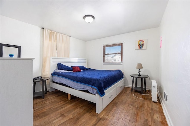 bedroom featuring visible vents, baseboards, and wood finished floors