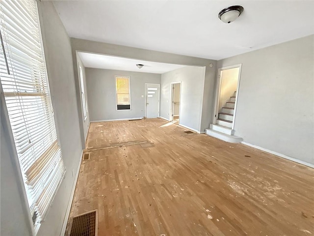 unfurnished living room featuring stairway, wood finished floors, and visible vents