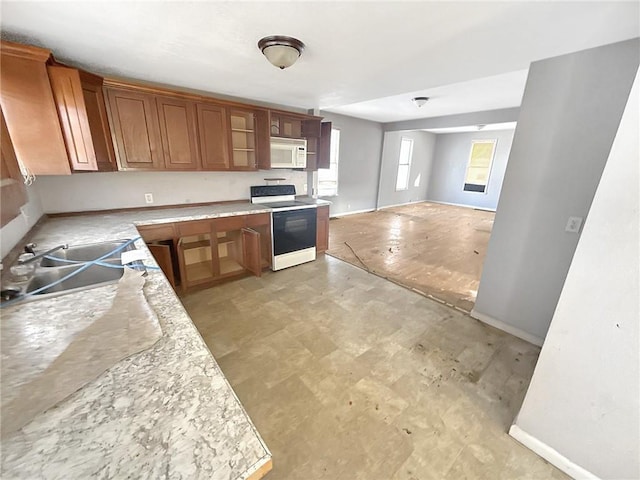 kitchen with light countertops, electric stove, white microwave, and a sink