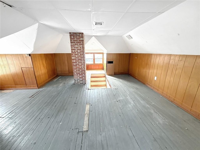 additional living space with hardwood / wood-style floors, lofted ceiling, visible vents, and wood walls