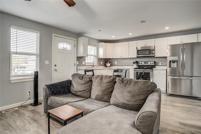 living room featuring recessed lighting, visible vents, baseboards, and light wood-style floors