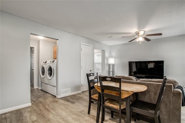 dining area featuring light wood finished floors, visible vents, baseboards, ceiling fan, and independent washer and dryer