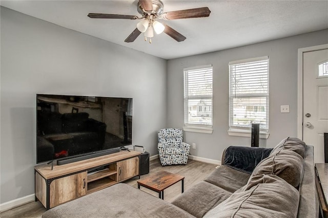 living area with baseboards, a ceiling fan, and wood finished floors