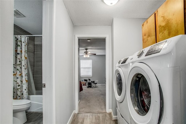 clothes washing area featuring a ceiling fan, cabinet space, separate washer and dryer, and a textured ceiling