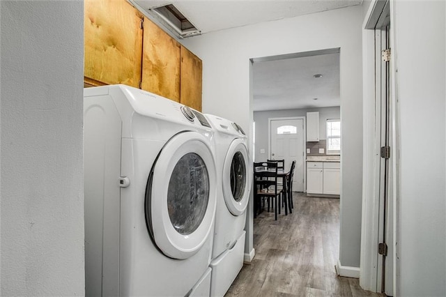 laundry room featuring washing machine and dryer, cabinet space, and wood finished floors