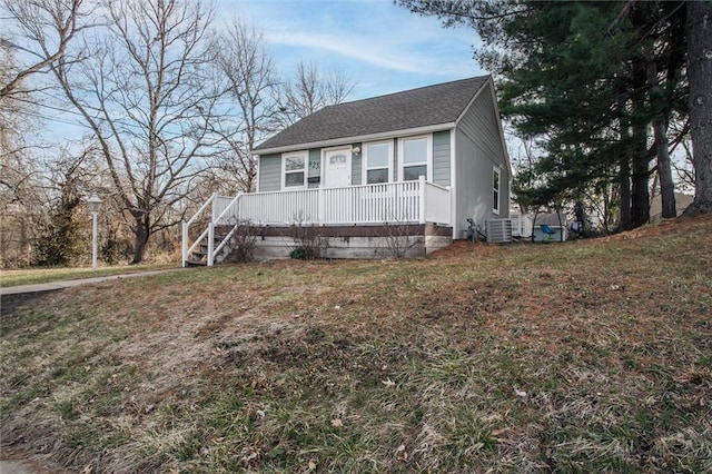 view of front of home featuring central air condition unit, a porch, a front lawn, and roof with shingles