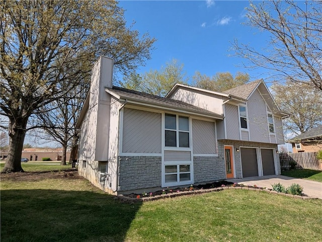 split level home with an attached garage, driveway, a front lawn, and fence