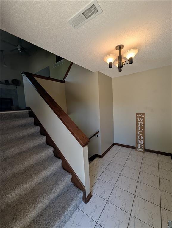 1900 SE 6th Ter, Lees Summit, MO 64063 - stairway with marble look tile flooring, a textured ceiling, a ceiling fan, baseboards, and a chandelier