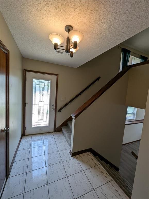 1900 SE 6th Ter, Lees Summit, MO 64063 - foyer entrance featuring a textured ceiling, light marble finish flooring, baseboards, stairs, and a chandelier