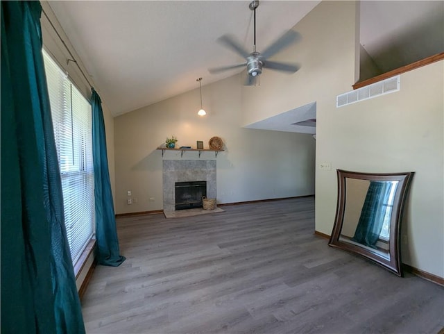 1900 SE 6th Ter, Lees Summit, MO 64063 - unfurnished living room with a tiled fireplace, a ceiling fan, wood finished floors, high vaulted ceiling, and baseboards