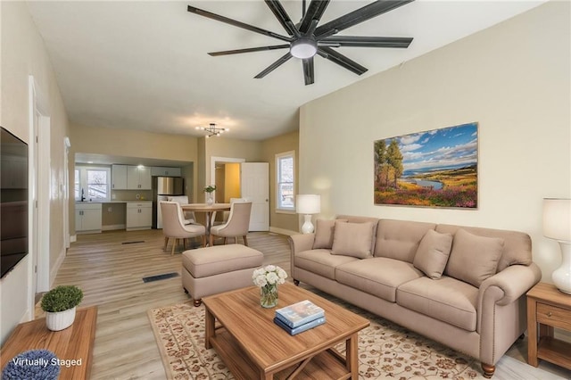 living room featuring light wood-style flooring, baseboards, and ceiling fan