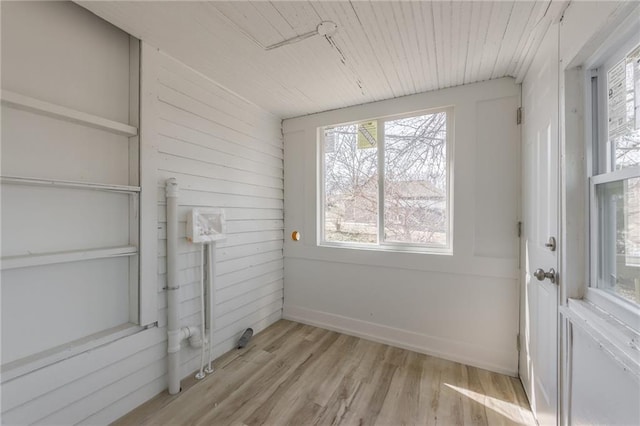 interior space with baseboards, wood walls, wood ceiling, and light wood-style floors