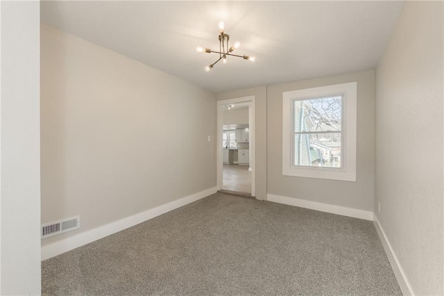 unfurnished room with a chandelier, visible vents, carpet flooring, and baseboards