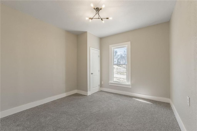 empty room with baseboards, carpet, and a chandelier