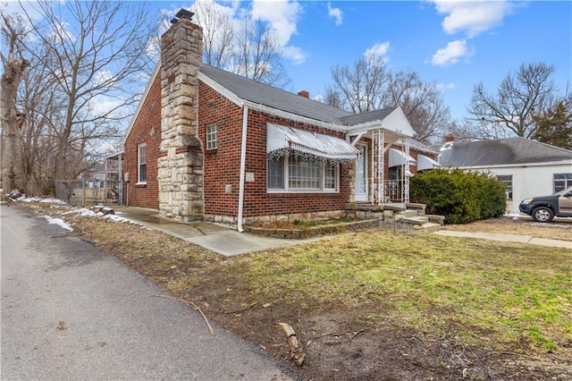 view of front of property with a front lawn, brick siding, and a chimney