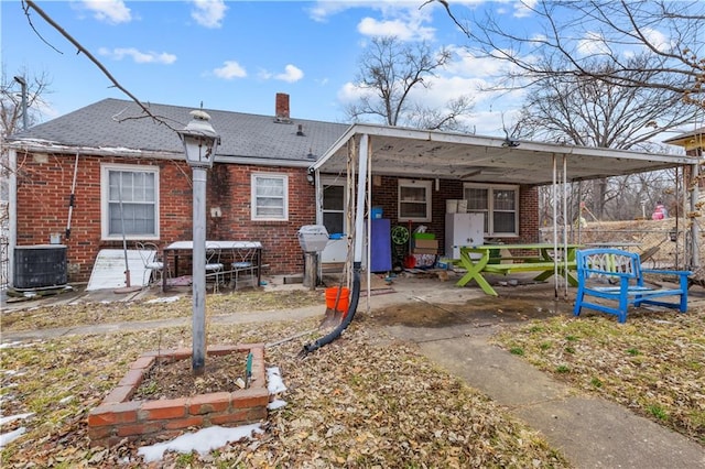 view of front facade featuring cooling unit, brick siding, and a chimney