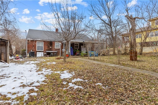 view of front of house featuring brick siding, central AC, a chimney, and fence