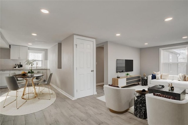 living room featuring recessed lighting, baseboards, and light wood finished floors