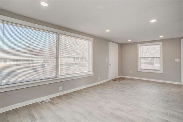 empty room featuring visible vents, baseboards, and light wood-style floors