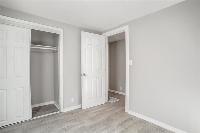 unfurnished bedroom featuring baseboards, a closet, and wood finish floors